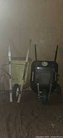 Two wheelbarrows upright against wall