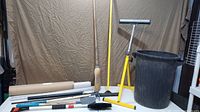 Group shot showing roller stand, brooms, garbage bin and assorted tools on table