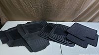 All six car mats displayed on table: two large rubber, two medium rubber, two carpeted