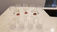 All 12 glasses arranged: front row four crystal lowballs, middle row three Stella Artois beer glasses, back row five wine glasses