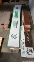 Stacked flooring boxes labeled Floornature and Grandeur with loose planks