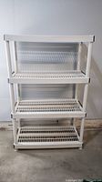 Full view of white plastic four-tier shelving unit