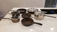 Group shot of all seven pans and four lids on countertop