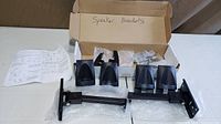 Box opened showing two arm assemblies, four speaker clamps, hardware bags and instructions