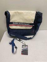 Front view of BMW Motorsport messenger bag with lanyard and pass displayed