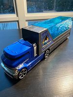 Left side view of blue cab and translucent blue container on trailer