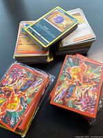 Stacks of Pokémon cards beside sealed Charizard graphic sleeve packs