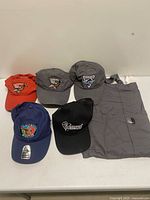 Group shot of six hats and grey apron on table