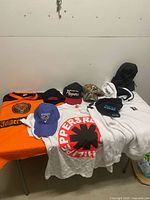 All items laid on table, showing clothing, caps, beanie, backpack