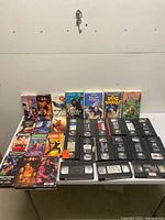 Wide view of entire lot on table showing sleeved tapes standing at back and loose tapes laid out front