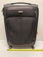 Front view of Samsonite suitcase showing wheels, front pocket and tape measure for width