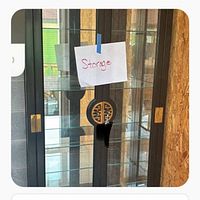 Front view of black lacquered glass curio cabinet showing doors, brass hardware and glass shelves