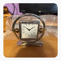 Front view of chrome and brass-tone Art Deco table clock on oval base