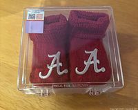 Crimson infant booties with Alabama logo in clear box