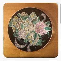 Front view of round cloisonné plate showing full floral and geometric design on black background