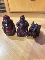Front view of three dark red resin figurines