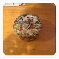 Top view of covered trinket box showing famille rose figural scene and scalloped rim