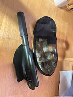 Shovel folded beside open camo sheath