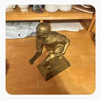 Side view of gold-tone football player statue on base