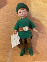 Front view of Peter Pan doll in green outfit with tag