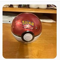 Front view of red and white Poké Ball tin, Pokémon Trading Card Game logo visible