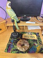 Group shot showing all four items: parrot figurine on stand, resin shell disk, Captain's Quarters sign, parrot print sheer fabric