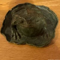 Front view of pottery frog sculpture on lily pad