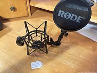 RØDE SM6 shock mount with attached pop filter on wooden surface