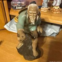 Front view of ceramic fisherman figurine showing face, body posture and missing pole