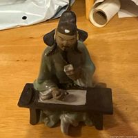 Front view of ceramic scholar figurine seated at desk