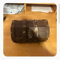 Closed wooden treasure chest style jewelry box on table