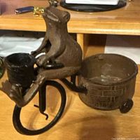 Side view of cast iron frog on bicycle showing front basket and rear tub