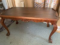Full view of solid wood coffee table with cabriole legs and carved apron