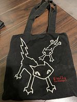 Front view of black Emily the Strange bag showing cat graphic and handles