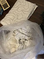 Folded curtain panels showing white fabric and grey squiggle pattern