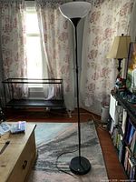 Full view of black torchiere lamp in room, showing height, base, cord