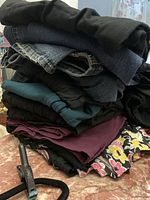 Stack of assorted folded pants, jeans, shorts, skirt