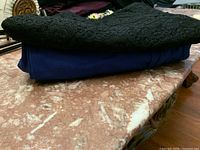 Blue pants and black lace skirt folded on table