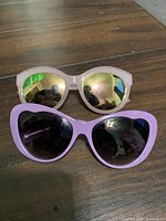 Front view purple glitter heart sunglasses and pink mirrored sunglasses