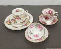 Three floral teacup groups with saucers and plate displayed