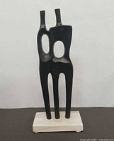 Front view of abstract black metal sculpture on wood base