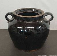 Front view of dark brown glazed ceramic pot with handles