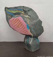 Front view showing grey glazed surface with pink vent-like element and blue, green, yellow accents