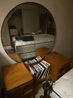 Full view of vanity with round mirror, twin side cabinets, central magazine rack
