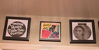 All three black-framed album cover prints mounted on wall