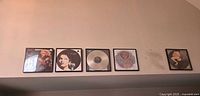 Full set of five framed vinyl pieces lined on shelf