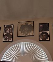 Three framed vinyl record displays above window: two Elvira records with cover images and one bat-shaped record in center