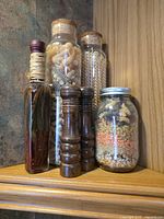 Group on right shelf: decorative bottle, two wood grinders, three cork-topped jars, one mason jar