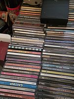 Stacks of assorted CD jewel cases showing spines with titles and artists