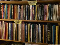 Two full shelves of paperback books with lot number notes visible